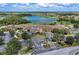 Aerial view of the clubhouse with a circular drive and beautifully manicured landscaping, adjacent to a lake and golf course at 7803 Grand Estuary Trl # 303, Bradenton, FL 34212