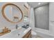 Stylish bathroom with mosaic tile in shower and round wood-framed mirror at 8847 Colonels Ct, Sarasota, FL 34240