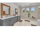 Elegant bathroom featuring dual vanities, a glass-enclosed shower with windows, and neutral finishes at 8847 Colonels Ct, Sarasota, FL 34240