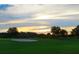 Scenic golf course view featuring vibrant green landscape, sand trap and sunset at 8847 Colonels Ct, Sarasota, FL 34240