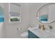 Stylish powder room features a blue vanity, a modern circular mirror, and natural light from the window at 8847 Colonels Ct, Sarasota, FL 34240