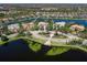 Aerial view of the home near the lake featuring circular drive, lush landscaping, and surrounding neighborhood at 7921 Waterton Ln, Lakewood Ranch, FL 34202
