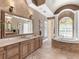 Lavish bathroom featuring a soaking tub, stone tile, and dual sinks with a large mirror at 7921 Waterton Ln, Lakewood Ranch, FL 34202