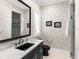 Stylish bathroom with a black vanity, marble countertop, and elegant floral wallpaper at 7921 Waterton Ln, Lakewood Ranch, FL 34202