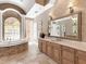 Luxurious bathroom featuring a soaking tub, stone-tiled walls, and a large vanity mirror at 7921 Waterton Ln, Lakewood Ranch, FL 34202