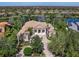 Aerial view of grand home with lush landscaping, columns, and circular drive set amongst manicured grounds at 7921 Waterton Ln, Lakewood Ranch, FL 34202