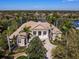 Aerial view of a stunning home with manicured landscaping, columns, and a circular driveway near the lake at 7921 Waterton Ln, Lakewood Ranch, FL 34202