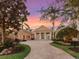 Beautiful, expansive property with a circular brick driveway and palm tree landscaping under a colorful sunset sky at 7921 Waterton Ln, Lakewood Ranch, FL 34202