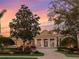 Beautiful home with lush landscaping, a circular driveway, and a grand entrance at sunset at 7921 Waterton Ln, Lakewood Ranch, FL 34202