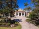 Elegant home featuring a circular driveway, mature landscaping, and classic architectural details at 7921 Waterton Ln, Lakewood Ranch, FL 34202