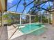 An enclosed pool with an attached hot tub, lush greenery, and lake views at 7921 Waterton Ln, Lakewood Ranch, FL 34202