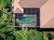 Aerial view of a screened-in pool with a spa surrounded by lush landscaping and a tile roof at 7921 Waterton Ln, Lakewood Ranch, FL 34202