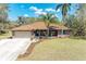Charming single-story brick home with lush landscaping, mature palms, and a two-car garage at 1127 133Rd E St, Bradenton, FL 34212