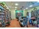 A cozy library space featuring floor-to-ceiling bookshelves and inviting tables and chairs for reading and relaxation at 1250 N Portofino Dr # 201, Sarasota, FL 34242