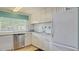 Galley kitchen featuring white cabinets, tiled backsplash and flooring, stainless dishwasher and white fridge at 1250 N Portofino Dr # 303, Sarasota, FL 34242
