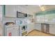 Galley kitchen with white cabinets, tile backsplash, stainless dishwasher, microwave, and tiled floors at 1250 N Portofino Dr # 303, Sarasota, FL 34242