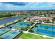 Aerial view of multiple tennis courts with lush landscaping, a nearby lake and beautiful residential homes at 13145 Amerigo Ln, Venice, FL 34293
