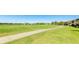Lush green golf course with a paved path and distant view of charming residential houses and a tranquil lake at 13719 Messina Loop # 101, Lakewood Ranch, FL 34211