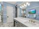 Bathroom with blue striped wallpaper, white cabinets, sleek fixtures, wall-mounted TV, and vanity with ample space at 15430 Blackmoor Ter, Lakewood Ranch, FL 34202