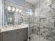 Modern bathroom with a glass shower featuring white and gray marble tiles, sleek fixtures and vanity with ample lighting at 15430 Blackmoor Ter, Lakewood Ranch, FL 34202