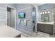 Stylish bathroom featuring blue striped wallpaper, a wall-mounted TV, and a vanity with ample counter space at 15430 Blackmoor Ter, Lakewood Ranch, FL 34202