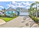 Beautiful home featuring turquoise shutters, a two-car garage, paver driveway, and lush landscaping at 15430 Blackmoor Ter, Lakewood Ranch, FL 34202