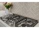 Close-up of kitchen stove with stainless steel hood and tile backsplash at 15430 Blackmoor Ter, Lakewood Ranch, FL 34202