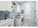 Laundry room featuring blue backsplash, a sink, white cabinetry, and modern machines at 15430 Blackmoor Ter, Lakewood Ranch, FL 34202