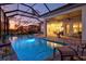 Evening view of a screened pool, spa, and outdoor living area at 15430 Blackmoor Ter, Lakewood Ranch, FL 34202