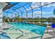 Sparkling pool and spa inside a screened lanai, complemented by beautiful landscaping and a serene lake view at 15430 Blackmoor Ter, Lakewood Ranch, FL 34202