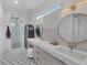 Elegant bathroom with dual round mirrors, vanity, decorative tile flooring, and glass shower at 16419 Kendleshire Ter, Lakewood Ranch, FL 34202
