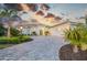 A well-manicured home exterior with a circular drive is enhanced by tropical plants and beautiful Florida sunset at 16419 Kendleshire Ter, Lakewood Ranch, FL 34202