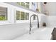 Bright kitchen featuring a stainless steel gooseneck faucet and undermount sink, framed by windows and a white countertop at 16419 Kendleshire Ter, Lakewood Ranch, FL 34202