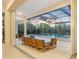 An outdoor pool patio with a seating area overlooks a stunning infinity pool and tropical landscaping beyond its screened enclosure at 16419 Kendleshire Ter, Lakewood Ranch, FL 34202