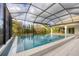A screened-in pool offers a refreshing escape, surrounded by lush greenery and clear blue waters at 16419 Kendleshire Ter, Lakewood Ranch, FL 34202