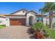 Beautiful single-story home with a tile roof, paver driveway, and lush tropical landscaping at 17216 Star Banks St, Wimauma, FL 33598