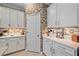 Bright kitchen features white cabinets, light stone countertops and modern backsplash at 17216 Star Banks St, Wimauma, FL 33598
