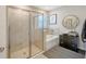 Bright bathroom featuring a walk-in shower, soaking tub, and a modern round mirror at 17715 Cantarina Cv, Bradenton, FL 34211