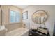 A bathtub sits beneath a window with plantation shutters, complemented by tasteful decor at 17715 Cantarina Cv, Bradenton, FL 34211