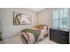 Comfortable bedroom with twin bed and colorful painting and natural light from the window at 17715 Cantarina Cv, Bradenton, FL 34211