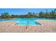 Expansive community pool with brick paver deck, lounge chairs, and lush landscaping in the background at 17715 Cantarina Cv, Bradenton, FL 34211