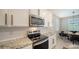 Modern kitchen featuring white cabinets, stainless steel appliances, granite countertops, and tile backsplash at 17715 Cantarina Cv, Bradenton, FL 34211