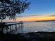 Calm waterfront view featuring a peaceful pier extending into the water during a colorful sunset at 1815 Palma Sola Blvd, Bradenton, FL 34209