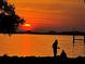 Picturesque waterfront view with a brilliant sunset reflecting on the water's surface, casting silhouettes at 1815 Palma Sola Blvd, Bradenton, FL 34209