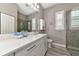Well-lit bathroom with double vanity, stone countertop, shuttered window, and glass enclosed shower at 22209 Deer Pointe Xing, Bradenton, FL 34202