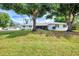 Front view of a cozy home with classic design, shaded by large trees on a green lawn at 3514 Laslo Ave, North Port, FL 34287