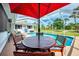 Outdoor seating area featuring a table with umbrella overlooking the refreshing enclosed backyard pool at 3514 Laslo Ave, North Port, FL 34287