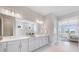 A light and airy bathroom featuring double sinks, white cabinets, and a view into the main bedroom at 3564 Santa Caterina Blvd, Lakewood Ranch, FL 34211