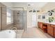 A bathroom featuring a tub, a glass shower, double sinks, and wood cabinets at 3750 Summerwind Cir, Bradenton, FL 34209