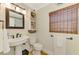Charming bathroom featuring a pedestal sink, decorative mirror, and bamboo window shade at 400 Nokomis S Ave, Venice, FL 34285